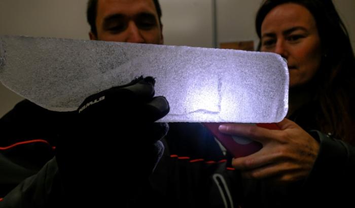 Des scientifiques examinent à la lumière d'un téléphone portable une carotte glaciaire antarctique dans un laboratoire à Bruxelles, le 15 juillet 2025 en Belgique