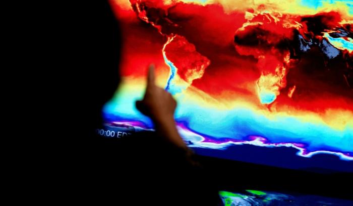 Un employé de la NASA devant une carte du monde affichant les informations transmises par satellites, lors d'une exposition immersive au siège de la NASA à Washington, le 21 juin 2023
