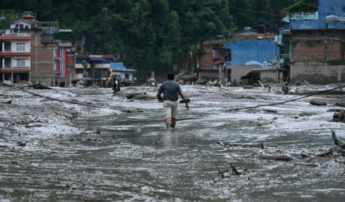 Un habitant marche dans une rue inondée de boue à Devighat, dans le district de Nuwakot au Népal, le 26 août 2026