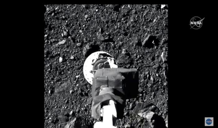 Image tirée d'une vidéo de la Nasa montrant le bras robotique de la sonde spatial Osiris-Rex entrant en contact avec l'astéroïde Bennu pour collecter des échantillons, le 21 octobre 2020