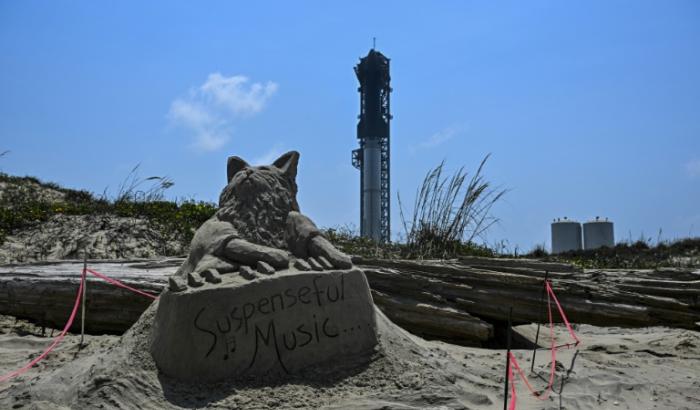 Une sculpture de sable représentant un chat jouant du piano et les mots "Suspenseful Music" est visible devant la fusée Starship à la base spatiale Starbase de SpaceX à Boca Chica, au Texas, le 5 juin 2024