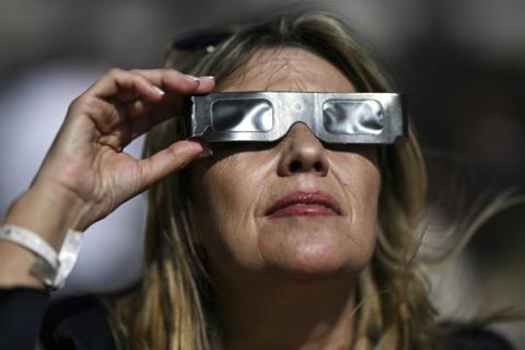 Une femme observe avec des lunettes protectrices une éclipse solaire partielle à Ericeira, au Portugal, le 29 mars 2025