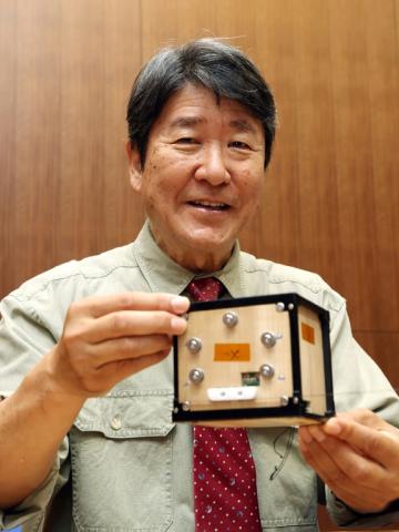 Takao Doi, astronaute et professeur à l'université de Kyoto, tient le premier satellite en bois au monde, baptisé LignoSat, lors d'une conférence de presse sur le campus de l'université à Kyoto, le 28 mai 2024
