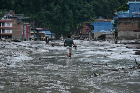 Un habitant marche dans une rue inondée de boue à Devighat, dans le district de Nuwakot au Népal, le 26 août 2026