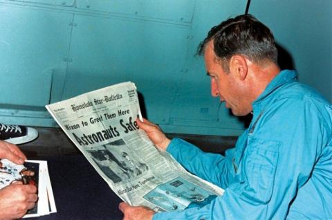 Jim Lovell en train de lire le journal évoquant le sauvetage périlleux d'Apollo 13 le 17 avril 1970, à bord de l'USS Iwo