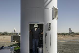 n technicien pose dans l'embrasure de l'un des 64 récepteurs du réseau MeerKAT dans le parc national MeerKAT, le 26 mars 2025.