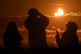 Des gens ovbservent une éclipse solaire partielle à New Brighton, banlieue côtière de la région de Christchurch, en Nouvelle-Zélande, le 22 septembre 2025