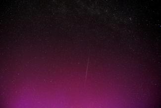 Une photo en pose longue montre une traînée laissée par un groupe de satellites Starlink de SpaceX, dans un ciel illuminé par des aurores boréales pendant la pluie annuelle d'étoiles filantes des Perséides, le 12 août 2024 à Wigry, en Pologne