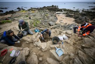 Des archéologues travaillent sur un squelette dans une tombe de l'âge du bronze, découvert à la suite d'une forte tempête, à Port-Joinville, sur l'île d'Yeu, le 10 septembre 2024