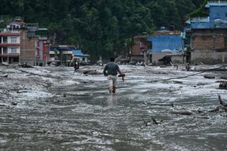 Un habitant marche dans une rue inondée de boue à Devighat, dans le district de Nuwakot au Népal, le 26 août 2026