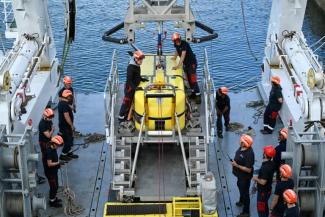 Des techniciens effectuent un test de lancement du robot sous-marin Ulyx à bord du navire scientifique Atalante amarré au port de Brest avant son départ, le 15 juin 2025 dans le Finistère