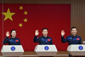 Les astronautes Wang Haoze, Cai Xuzhe et Song Lingdong saluent des personnes assistant à leur conférence de presse, à la veille de la mission Shenzhou-19, au centre de lancement de satellites de Jiuquan, dans le désert de Gobi, dans le nord-ouest de la Chine, le 29 octobre 2024