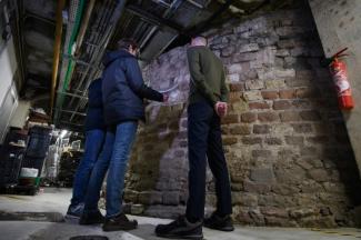 Gwendal Le Gourrierec (d), le directeur de supermarché, Maxime Werle (c), archéologue au Service Régional d'Archéologie, et l'historien Guillaume Marty (g), à côté des vestiges d'une tour romaine située dans le sous-sol d'un supermarché à Strasbourg, le 17 janvier 2025 dans le Bas-Rhin