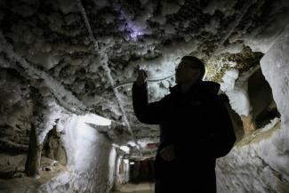Un scientifique examine les formes de glace qui sortent du pergélisol dans un tunnel souterrain à l'Institut du pergélisol à Iakuutsk, le 28 mars 2025 en Sibérie orientale